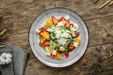 Portion of caesar salad with chicken on wooden table