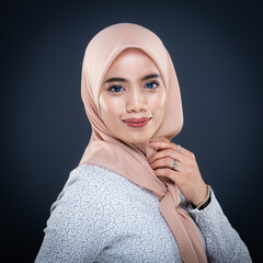 Close up portrait of a beautiful female model wearing traditional dress and hijab, a lifestyle apparel for Muslim women isolated on grey background. Idul Fitri and hijab fashion concept.