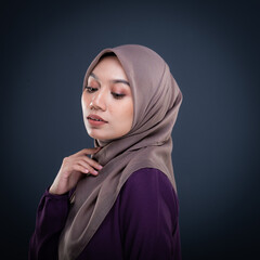 Close up portrait of a beautiful female model wearing traditional dress and hijab, a lifestyle apparel for Muslim women isolated on grey background. Idul Fitri and hijab fashion concept.