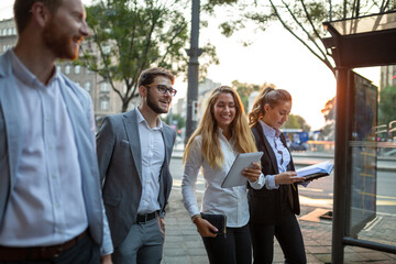 Group of cheerful young business people talking to each other while walking outdoors