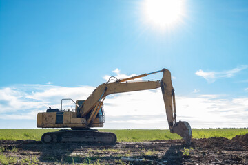 Excavator on the background of a green field.