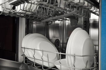 Dishwasher with white plates and cups on the kitchen . High quality photo