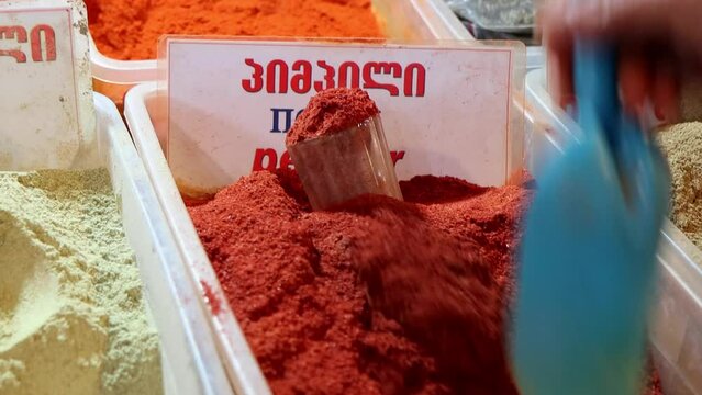 Ground red pepper. Colorful spices at oriental market close-up. Name of spices writes in English, Georgian and Russian letters.
