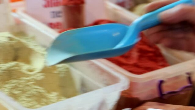 The vendor puts spices in the bag, close-up. Buying spices, seasonings on market concept, 4k. Name of spices writes in English, Georgian and Russian letters.