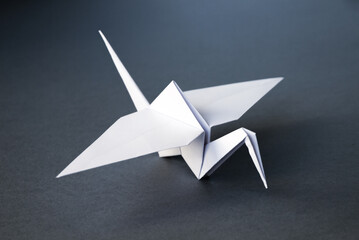 White paper crane origami isolated on a grey background