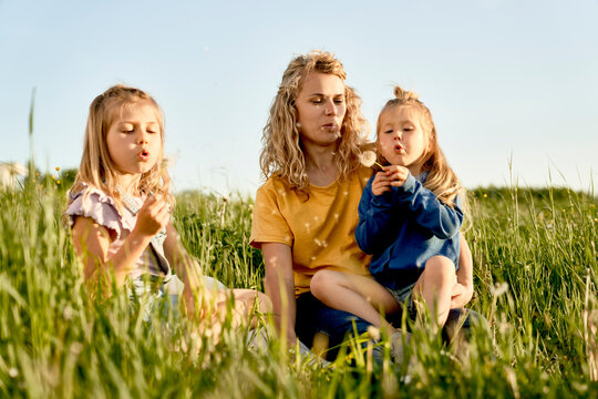 Woman with two daughters spending free time at the meadow