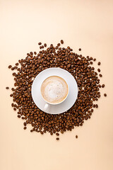 Coffee abstract, creative coffee cup and coffee beans beans on warm, neutral background.