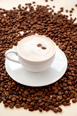 Coffee abstract, creative coffee cup and coffee beans beans on warm, neutral background.