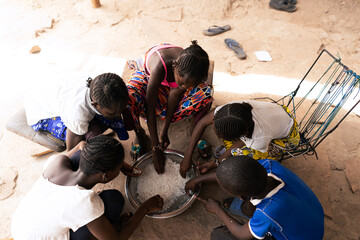 Overhead view of a group of African village children sharing a simple meal of rice; malnutrition concept - obrazy, fototapety, plakaty