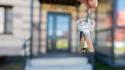 A woman holds the keys to a new house. Close-up of a female hand. Buying a property.