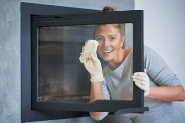 Picture of young woman cleaning fireplace glass doors