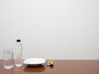 Dish cutlery with water bottle on the wooden table copy space white background