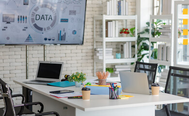 Modern decorated office workstation meeting room in company with desk full of stationary equipment,...