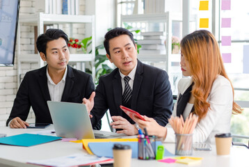 Group of cheerful Asian millennial professional successful male businessman and female businesswoman in formal suit sitting smiling holding fists up together celebrating customer agreement deal done