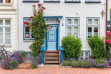 Fototapeta na wymiar Flowers at the front door of a white house in Gluckstadt, Germany