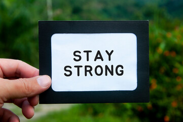 Hand holding notepad with text - Stay strong. Motivational concept