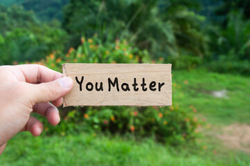 Hand holding wooden banner with text - You matter.