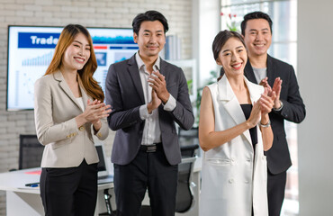 Obraz premium Group of Asian happy cheerful millennial professional successful male businessmen and female businesswomen in formal suit standing clapping hands applauding greeting celebrating together in office