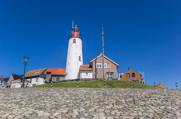 White lighthouse and houses on the top of the basalt stone dike in Urk, Netherlands