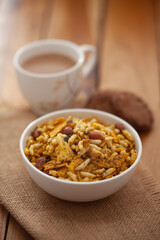 Close-Up of crunchy Indian mixture snacks with hot tea or Coffee time and handmade cookies (biscuits). Studio shoot at declined angle.