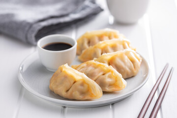 Chinese dumplings and soy sauce on plate.