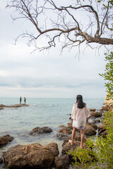 Young woman sitting on the rock at the beach.