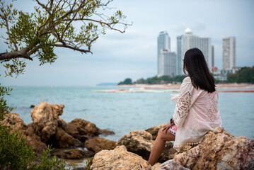 Young woman sitting on the rock at the beach.