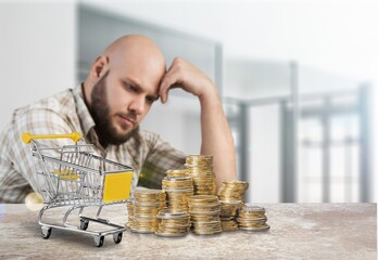 Shopping cart and man working on calculator with financial document.  Financial crisis concept.