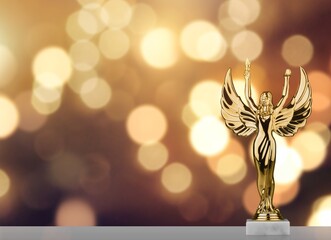 Golden Academy award statue against gold lights bokeh background.