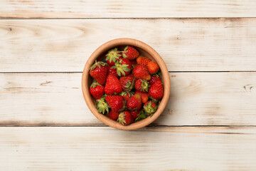 Bowl with fresh strawberries on wooden background, top view