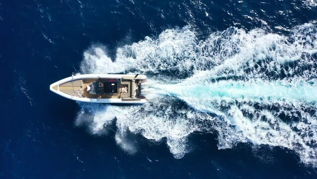 Aerial drone tracking video of luxury inflatable speed boat cruising in deep blue Aegean sea, Mykonos island, Cyclades, Greece