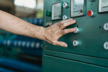 Obraz premium A close-up photo of a male hand holding a finger on a machine switch.