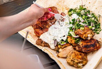 woman hand holding plastic fork with meat and sause outdoor