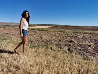 Beautiful middle-aged brunette woman walking in the countryside barefoot. Copy space