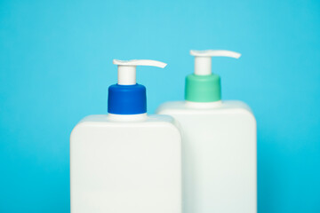 Shampoo or hair conditioner bottles with dispenser pump on blue background.