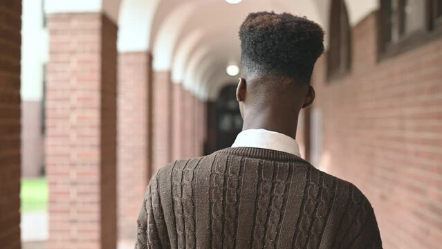 Rear view of young man seen walking along corridor