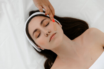 model with a headband and  with lifting tape on her face. Kinesio taping.
she covers her face with...