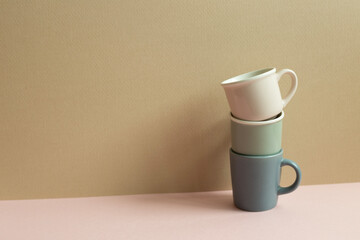 Stack of cups on pink table. beige wall background