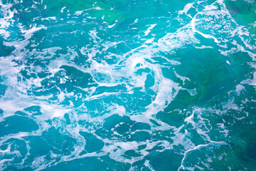 Water background, turquoise shallow sea water. Beautiful texture of sun glare on the water. sea foam