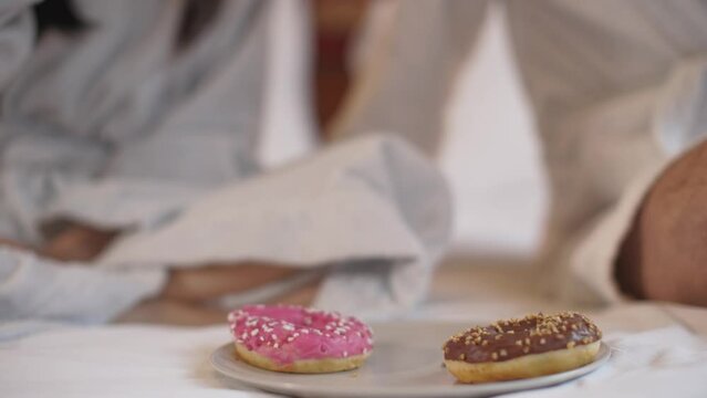 couple in a bathrobe having breakfast - detail on fruit juice and donuts