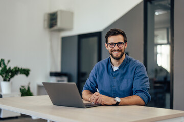 Portrait of a smiling man, posing for the camera while working online.