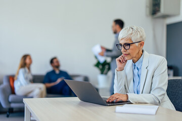 Serious-looking businesswoman, focused on her work, using a laptop, working online.