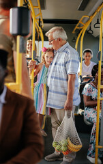 Grandfather and granddaughter  with groceries in city bus