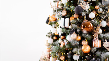 Christmas tree close up standing white wall background decorated white black gold color with light garland