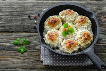 Chicken  meatballs in creamy mushroom sauce in cast iron skillet on wooden background. Top view, copy space, flat lay.