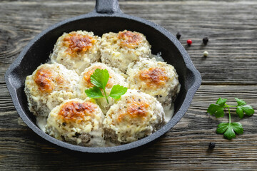 Chicken  meatballs in lemon cheesy sauce in cast iron skillet on wooden background. Top view, copy space, flat lay.