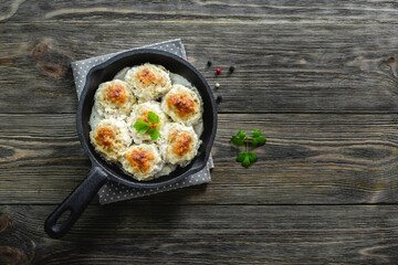 Baked chicken creamy meatballs in cast iron skillet on wooden background. Top view, copy space, flat lay.