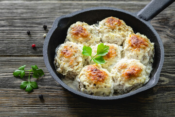 Chicken  meatballs in lemon cheesy sauce in cast iron skillet on wooden background. Top view, copy space, flat lay.
