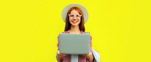 Portrait of modern young woman working with laptop on yellow background
