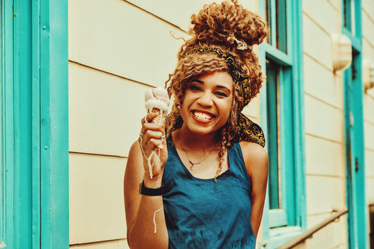 Young Adult Woman Afro Hair Smiling Eating Ice Cream Outdoors Summertime Looking At Camera Shot